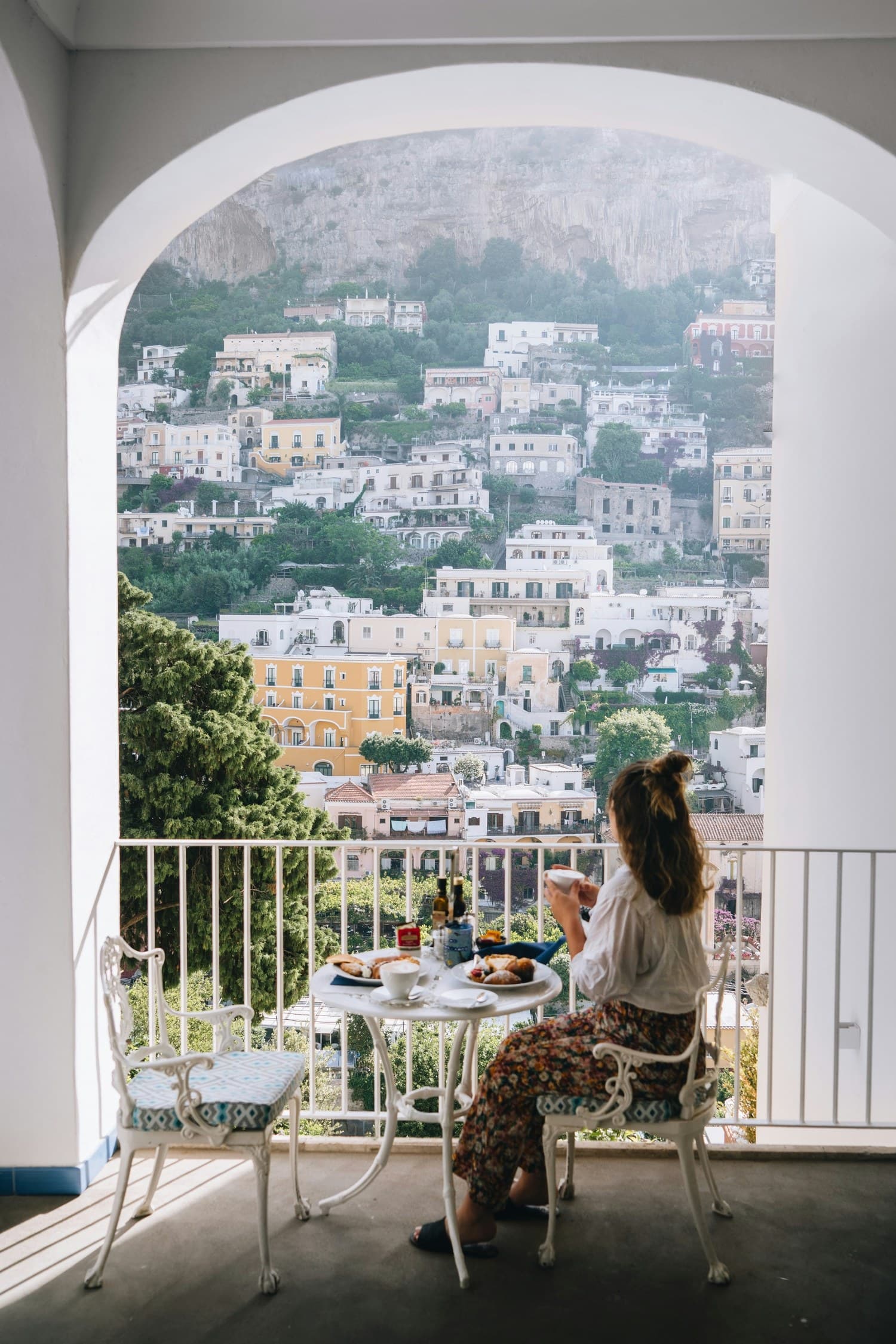 A Positano balcony with breakfast set for a guest, looking out at the Amalfi coast